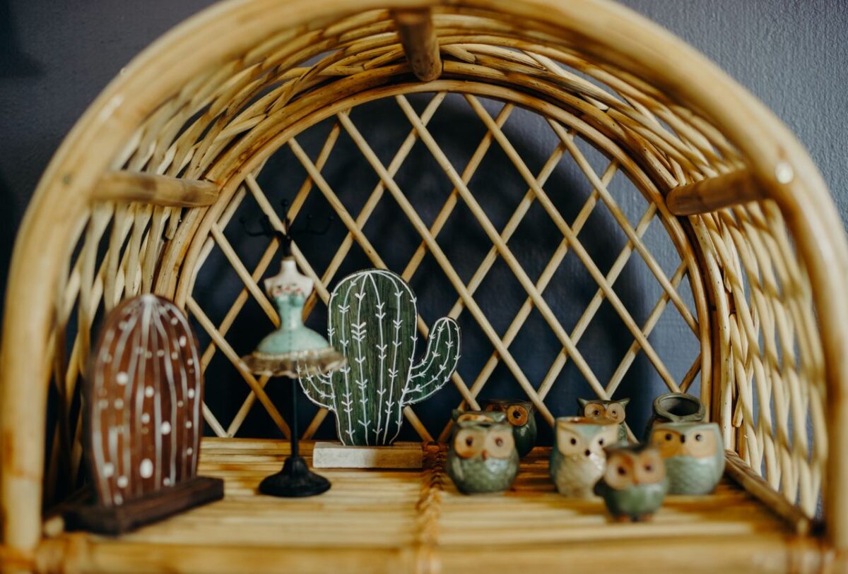 who-we-are Stylish shelf decor featuring owl figurines and cactus ornaments on a wicker shelf.